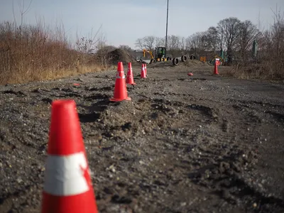 Slalom course with traffic cones and construction machines in the background