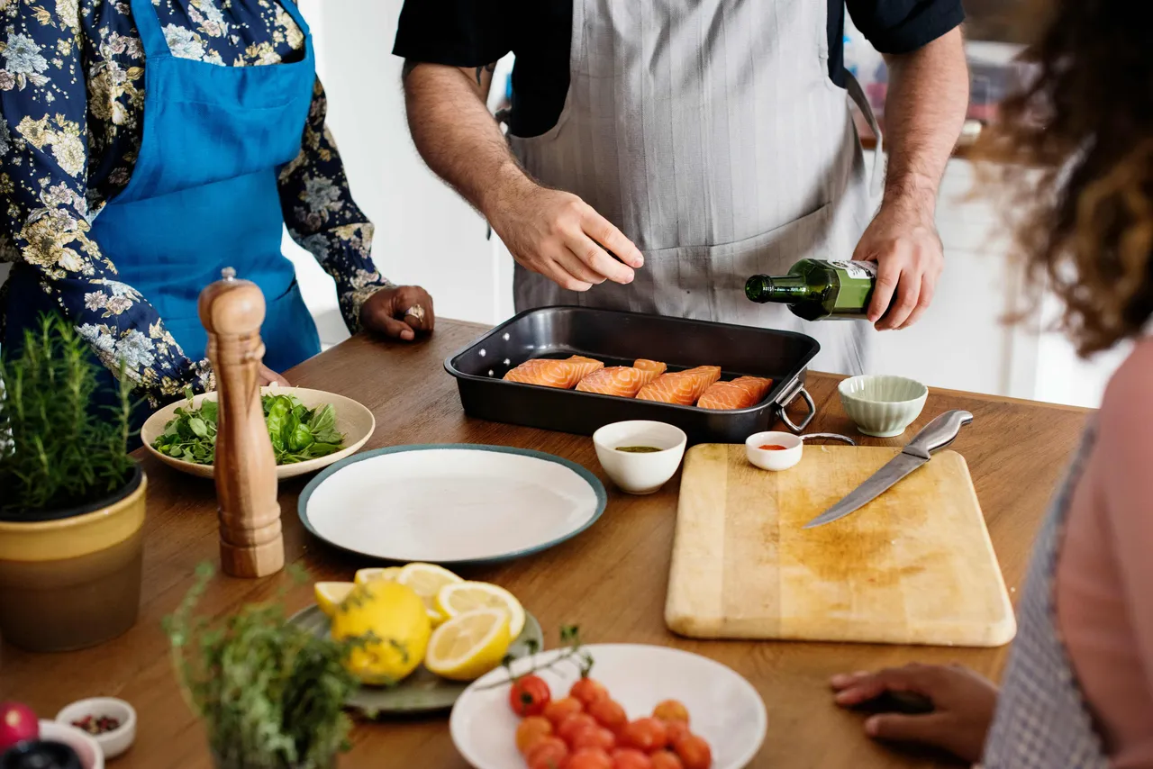 A group of people preparing a dish together with fish