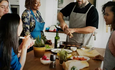A group of people preparing a dish together with fish