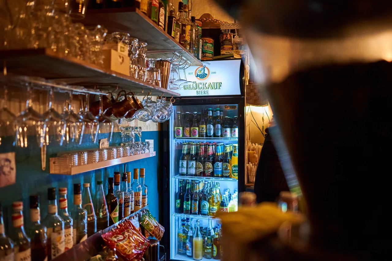 Well-stocked bar shelves with bottles and glasses in a small local bar