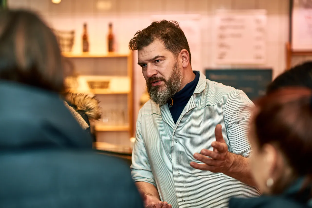 Bearded restaurant owner explaining his food to tour guests