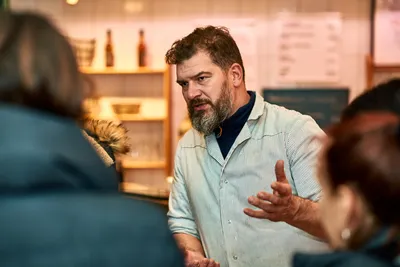   Bearded restaurant owner explaining his food to tour guests