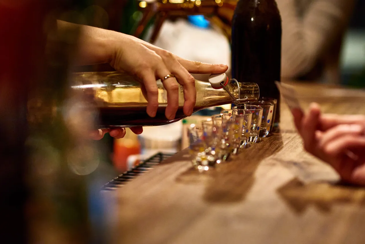 House-made schnapps being poured into a row of shot glasses