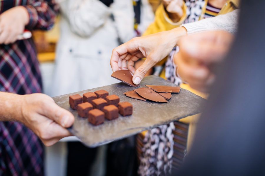 Tour guests taking handmade chocolate truffles from a slate tray during