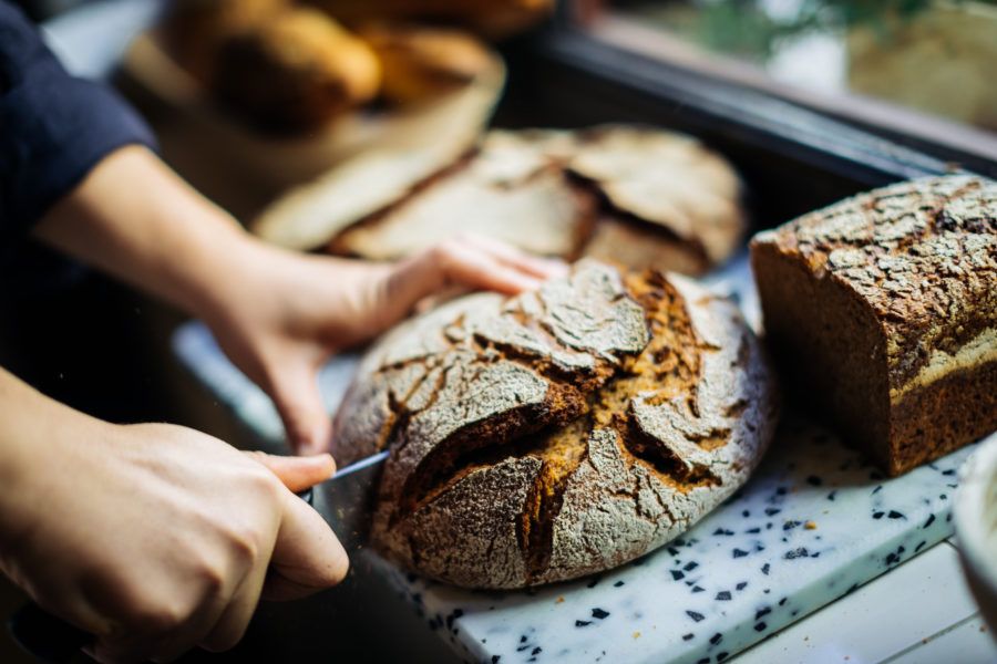 Baker slicing a crusty loaf of fresh sourdough bread