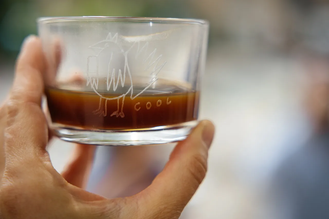 Hand holding a small glass of iced coffee