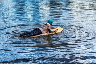 A person laying on an eFoil board on the water
