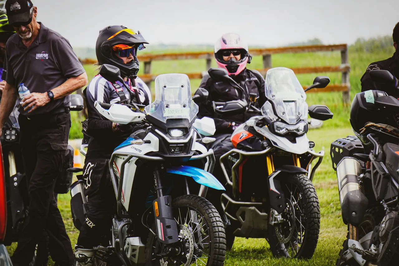 An enduro motorcycle sits parked on a dirt trail in the middle of a dense green forest.