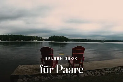 Experience gift box for couples – two red Adirondack chairs on a wooden dock overlooking a lake