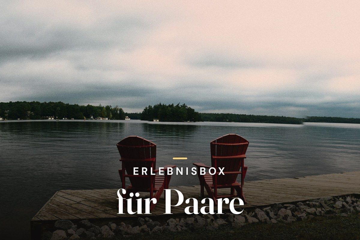 Experience gift box for couples – two red Adirondack chairs on a wooden dock overlooking a lake