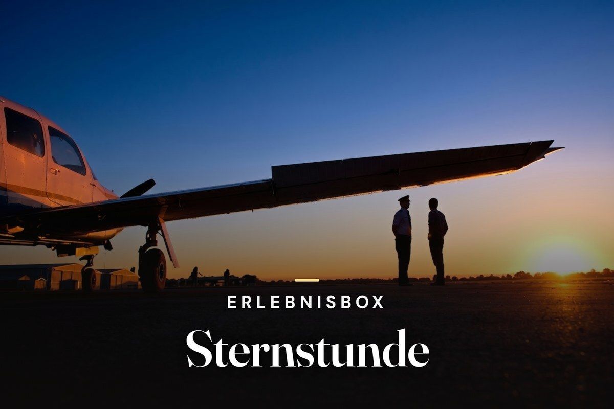 Pilot and passenger standing under the wing of a small aircraft at sunset, with the text "Erlebnisbox Sternstunde"