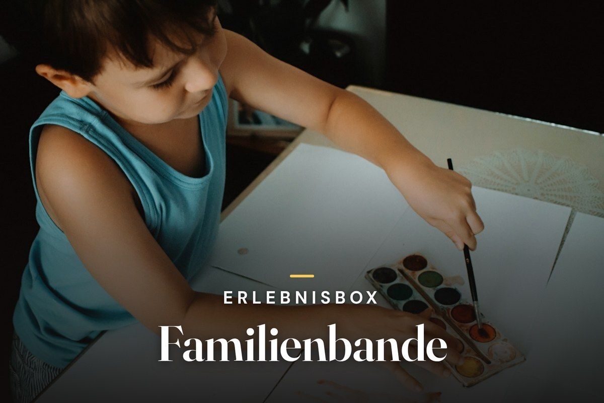 Child painting with watercolors at a table, with the text "Erlebnisbox Familienbande"