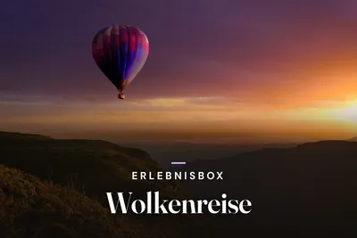 Colorful hot air balloon floating above hills at sunrise, with the text "Erlebnisbox Wolkenreise"