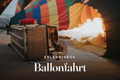 Burner flame inflating a colorful hot air balloon next to its basket at dawn, overlaid with the title Erlebnisbox Ballonfahrt