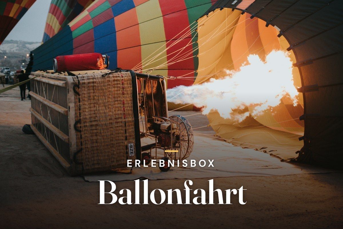 Burner flame inflating a colorful hot air balloon next to its basket at dawn, overlaid with the title Erlebnisbox Ballonfahrt