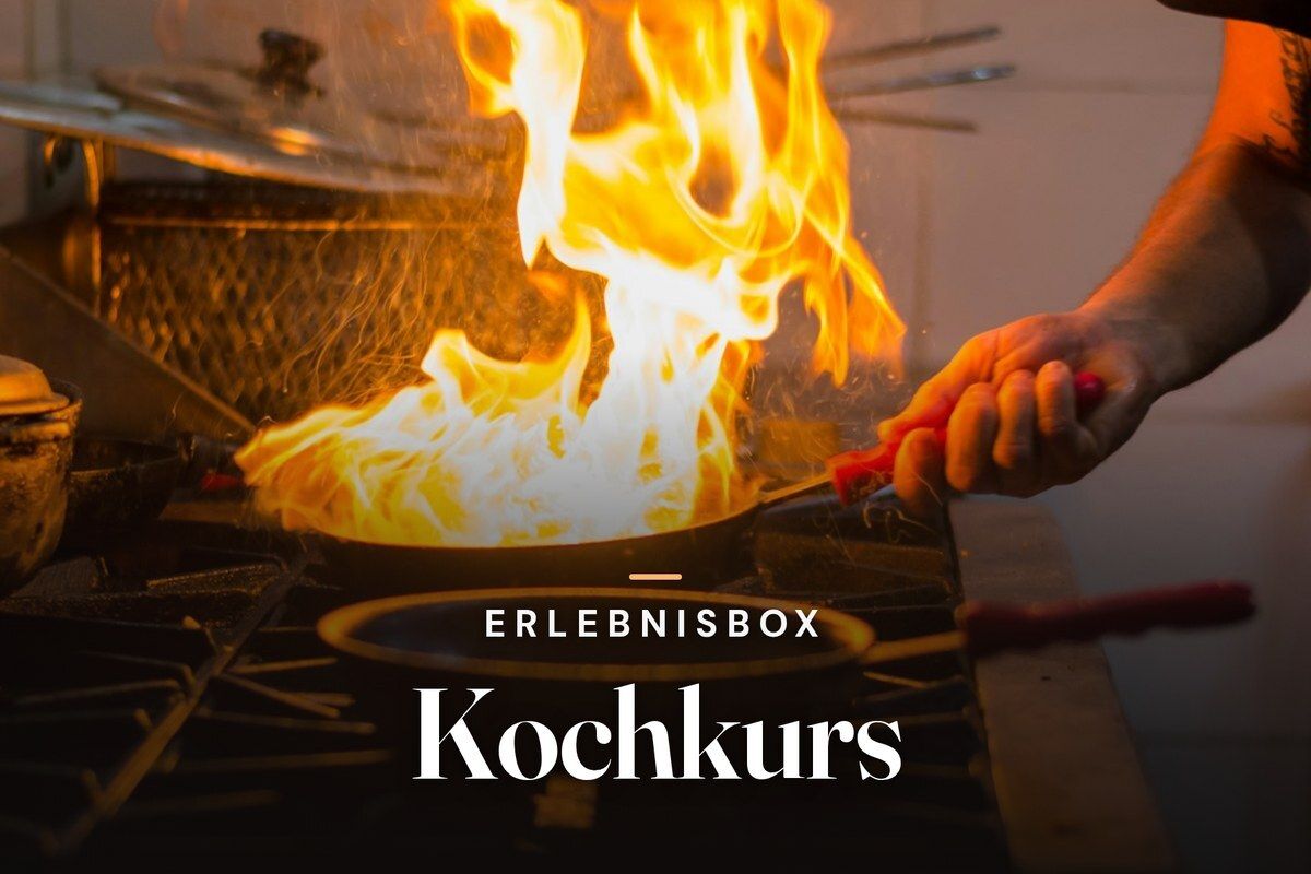 Chef flambéing food in a pan over a gas stove with high flames, overlaid with the title Erlebnisbox Kochkurs