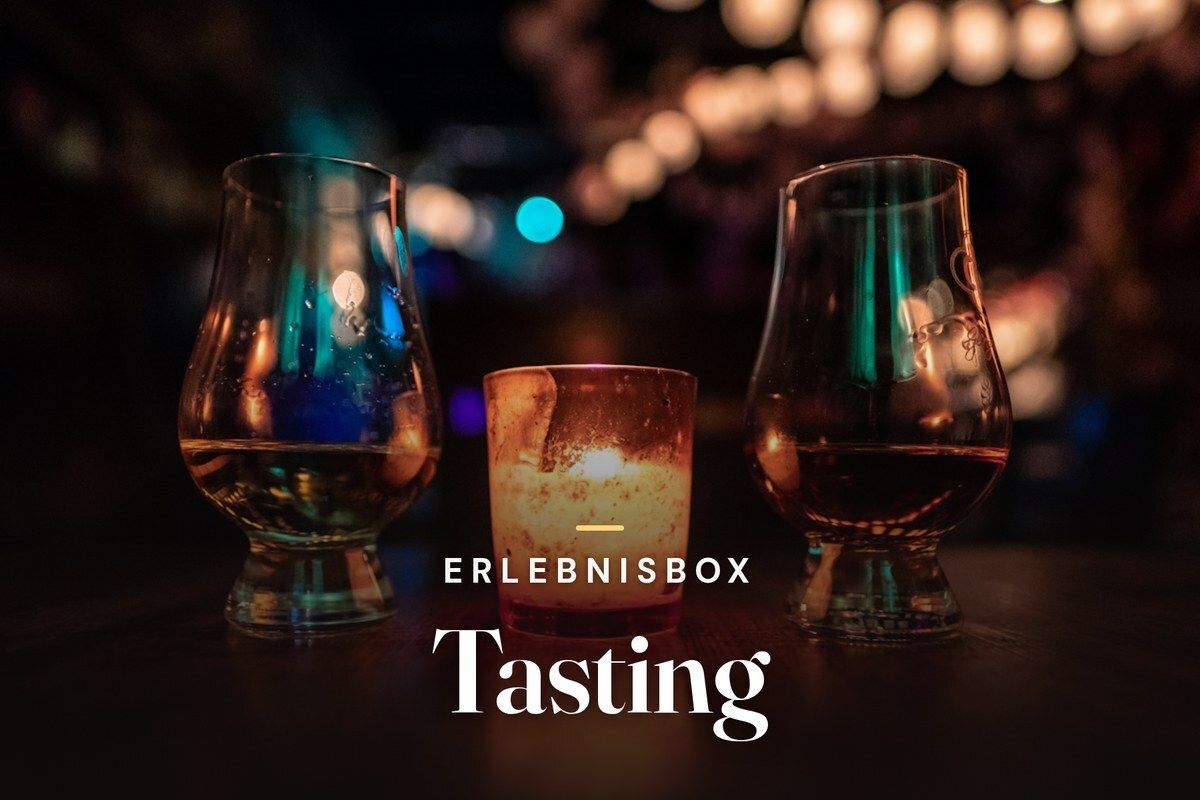 Two whisky tasting glasses next to a candle on a bar table at night, overlaid with the title Erlebnisbox Tasting