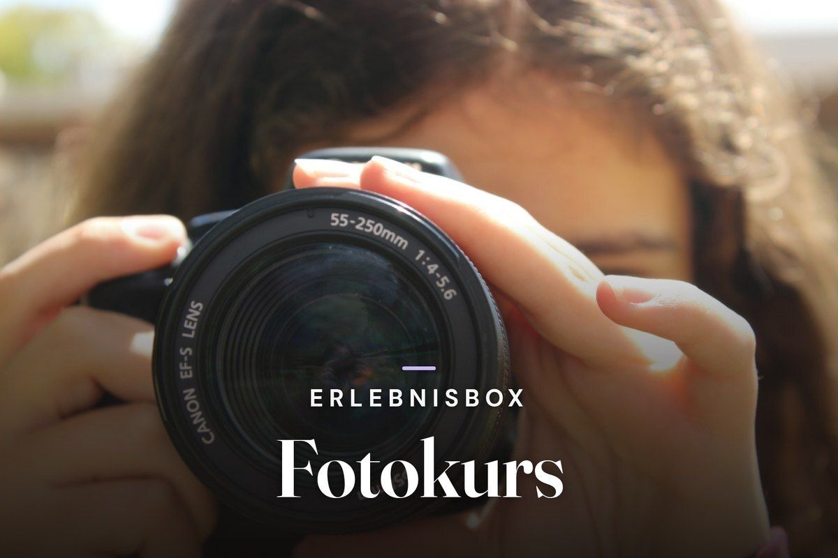 Person holding a DSLR camera up to their face in sunlight, overlaid with the title Erlebnisbox Fotokurs