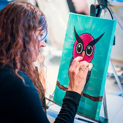 Women painting an owl on a canvas