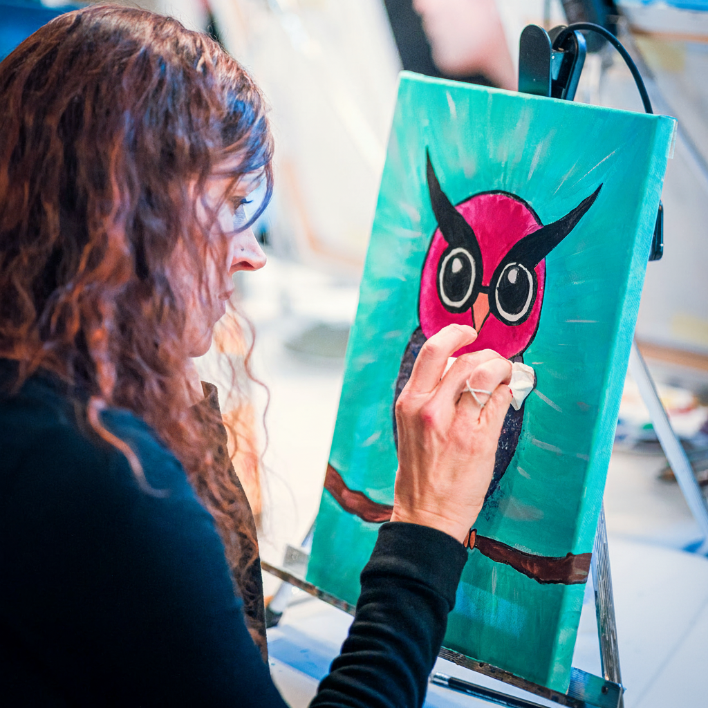 Women painting an owl on a canvas