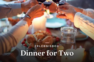 Hands toasting with red wine over a candlelit dinner table