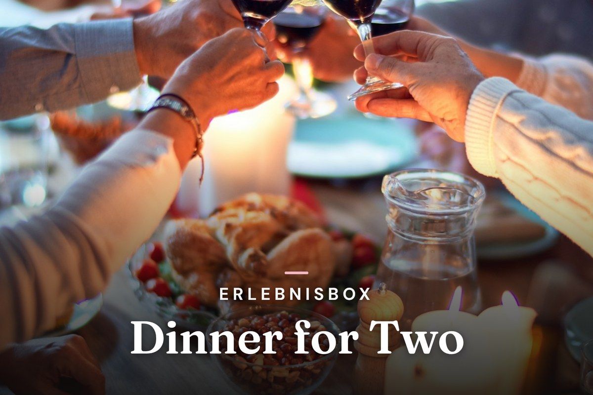 Hands toasting with red wine over a candlelit dinner table