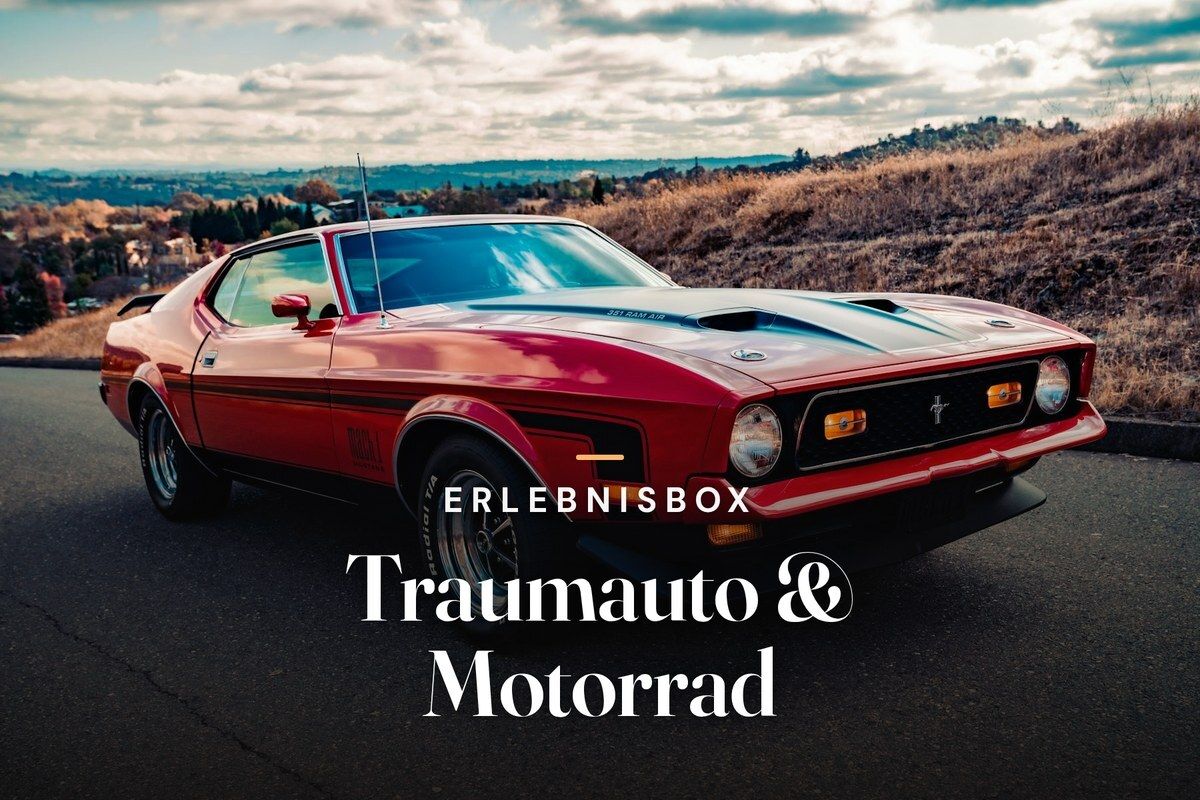 Red classic Ford Mustang with a black hood stripe parked on a hilltop road, with autumn hills and a cloudy sky behind it, with the text “Erlebnisbox – Traumauto & Motorrad”