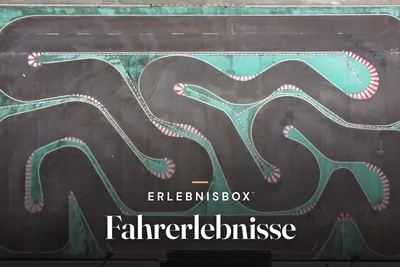 Aerial view of a winding go-kart track with turquoise run-off areas and red-and-white curbs, with the text “Erlebnisbox – Fahrerlebnisse”