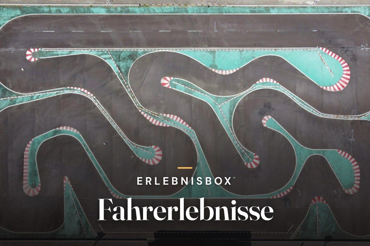 Aerial view of a winding go-kart track with turquoise run-off areas and red-and-white curbs, with the text “Erlebnisbox – Fahrerlebnisse”