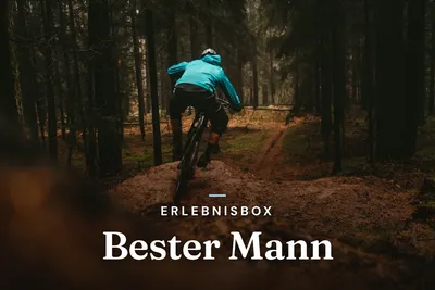 Mountain biker riding a dirt trail through a dark forest