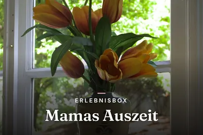 Orange tulips in a vase in front of a window with green garden view