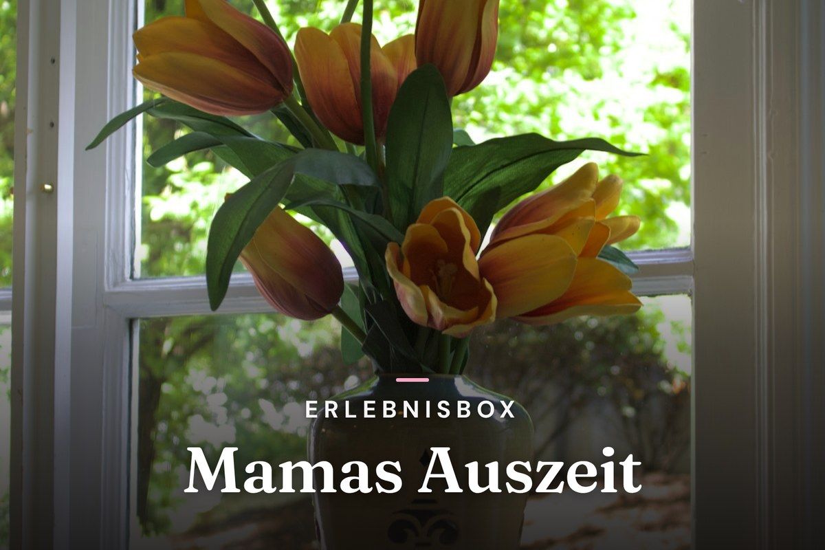 Orange tulips in a vase in front of a window with green garden view