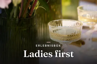 Sparkling wine in a crystal coupe next to a vase of flowers