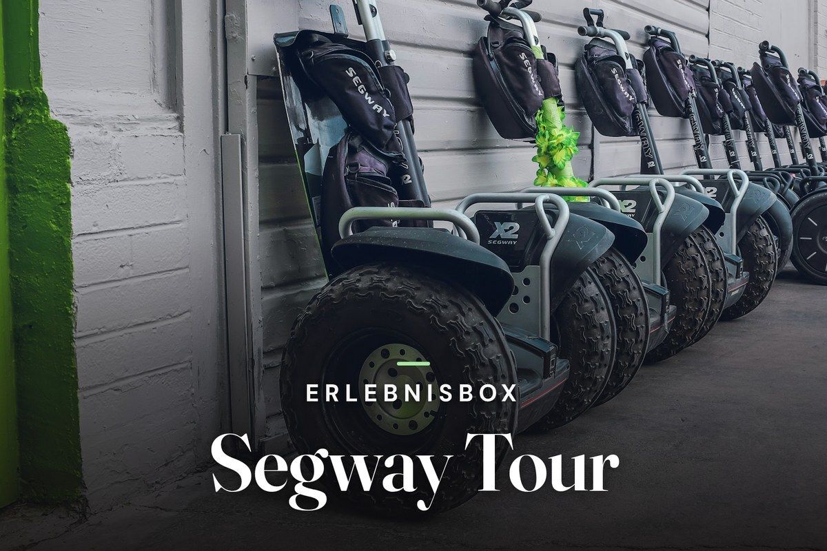 A row of Segway X2 off-road scooters with chunky tyres parked against a grey wall, with the text “Erlebnisbox – Segway Tour”