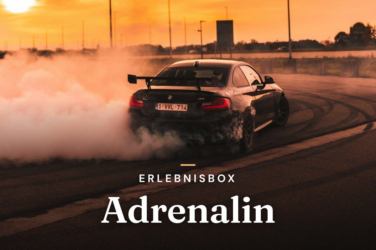 Black sports car drifting on a track with tire smoke at sunset