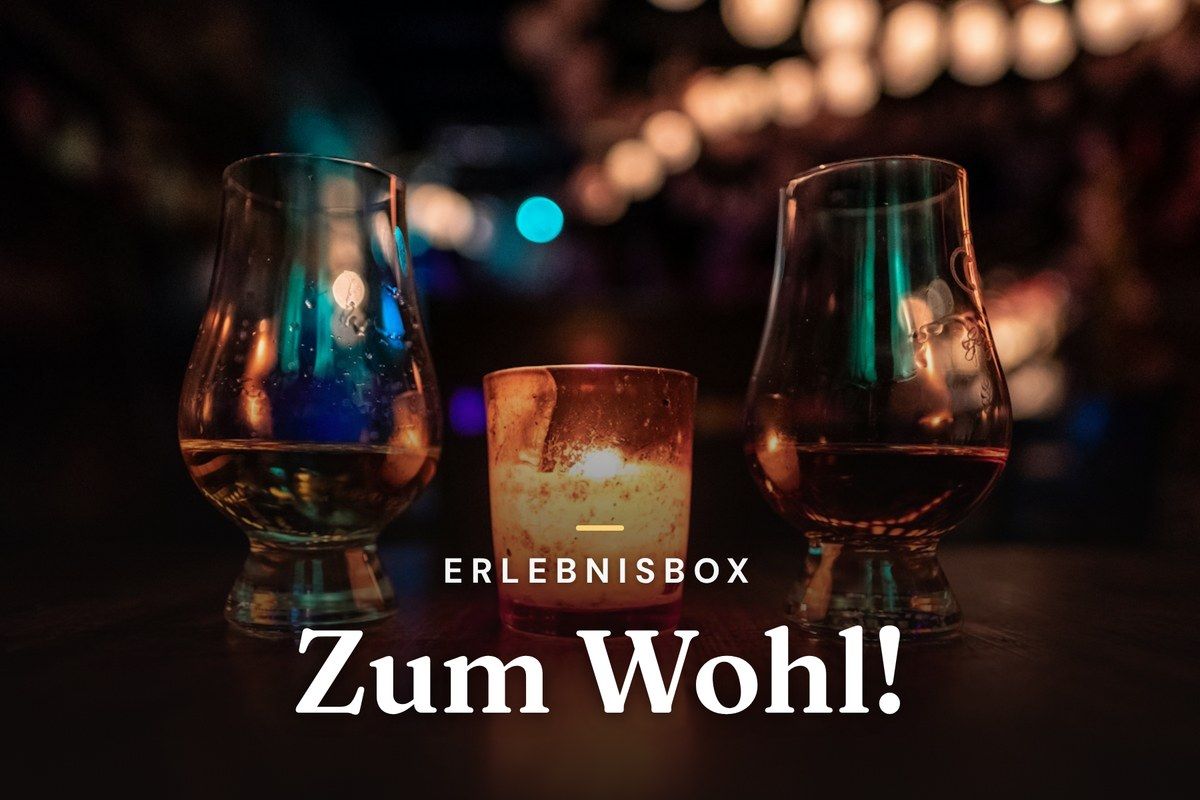 Two whisky tasting glasses beside a candle in a dimly lit bar