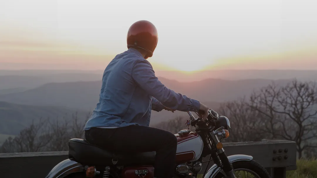 A person admiring the sunset from a motorbike