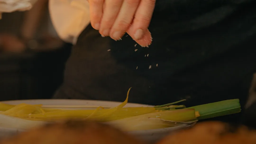 A person seasoning a dish