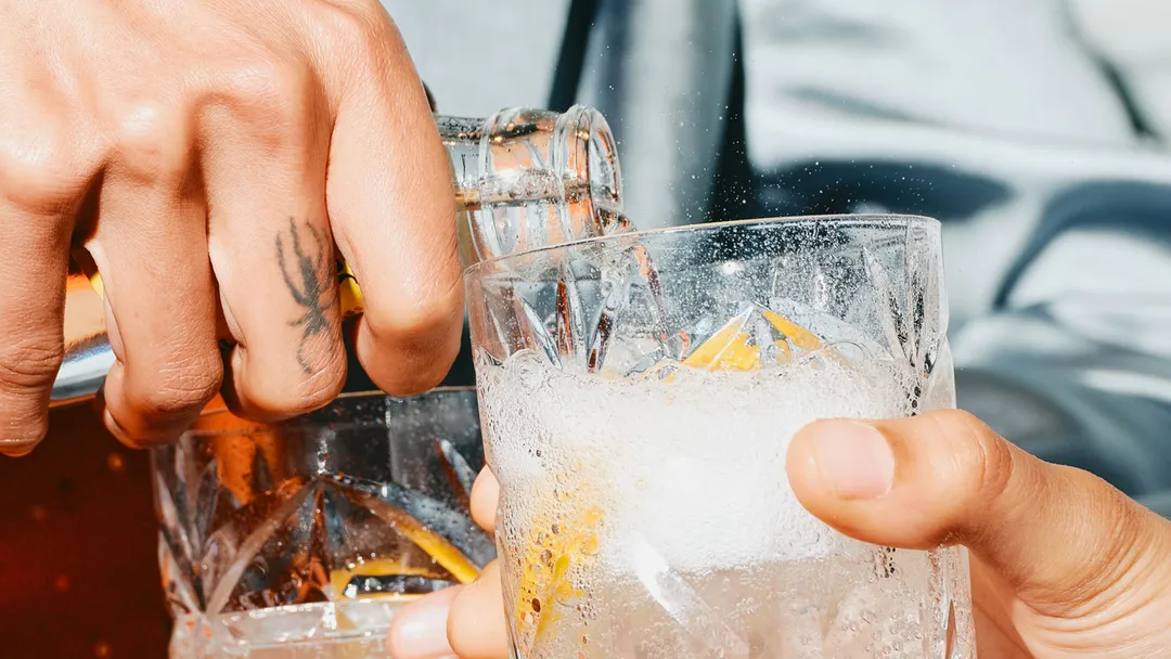 A person pouring a drink in a glass