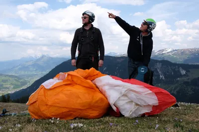 Two people with an unfolded paraglide looking around