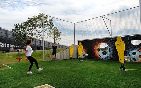 Young woman aiming at a football target wall on an outdoor footgolf field