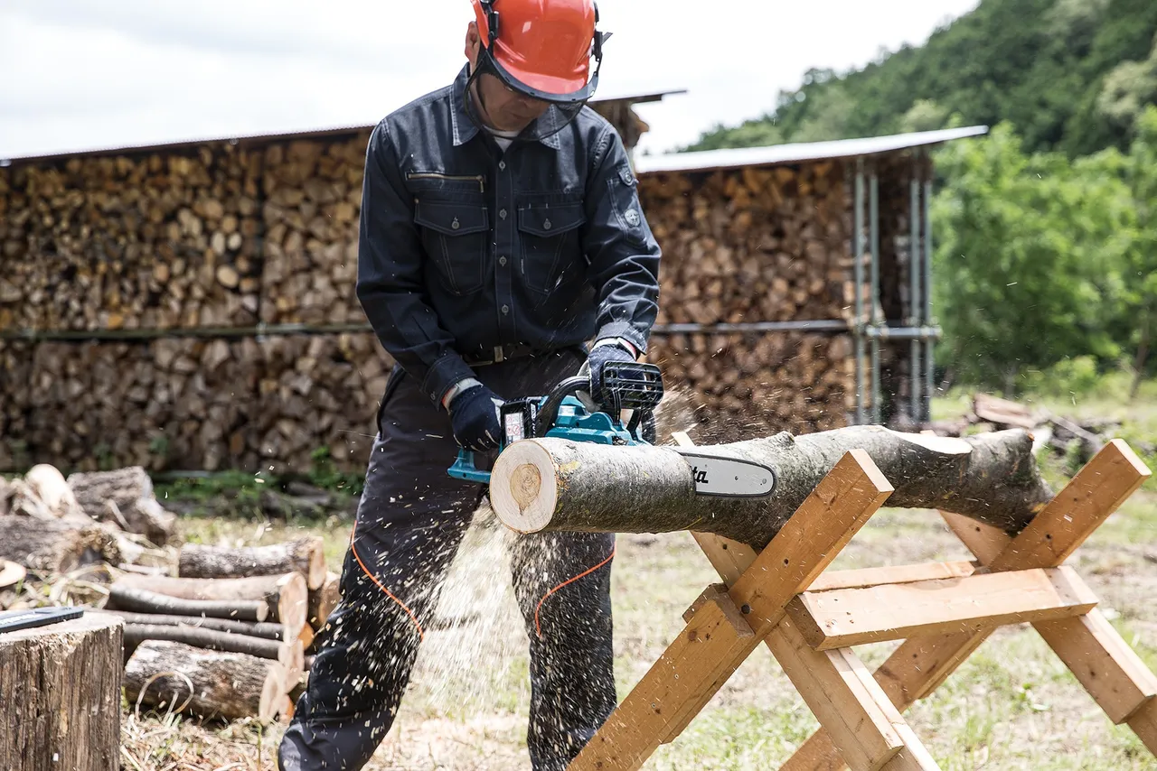 Man sawing a tree trunk with a chainsaw
