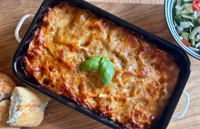 A lasagne fresh out of the oven garnished with basil