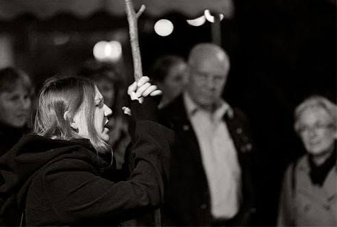 A woman in a spooky costume explaining something to a group of people