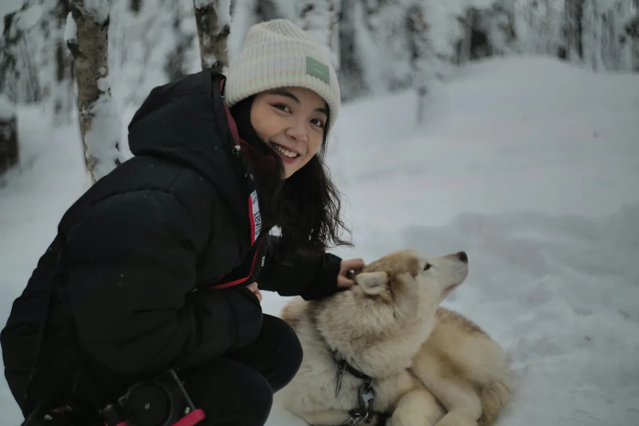 Woman kneeling in the snow petting a husky during a winter hike