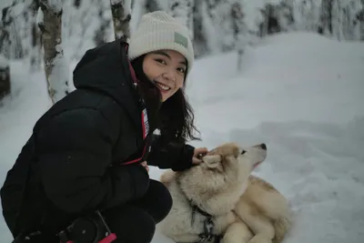 Woman kneeling in the snow petting a husky during a winter hike