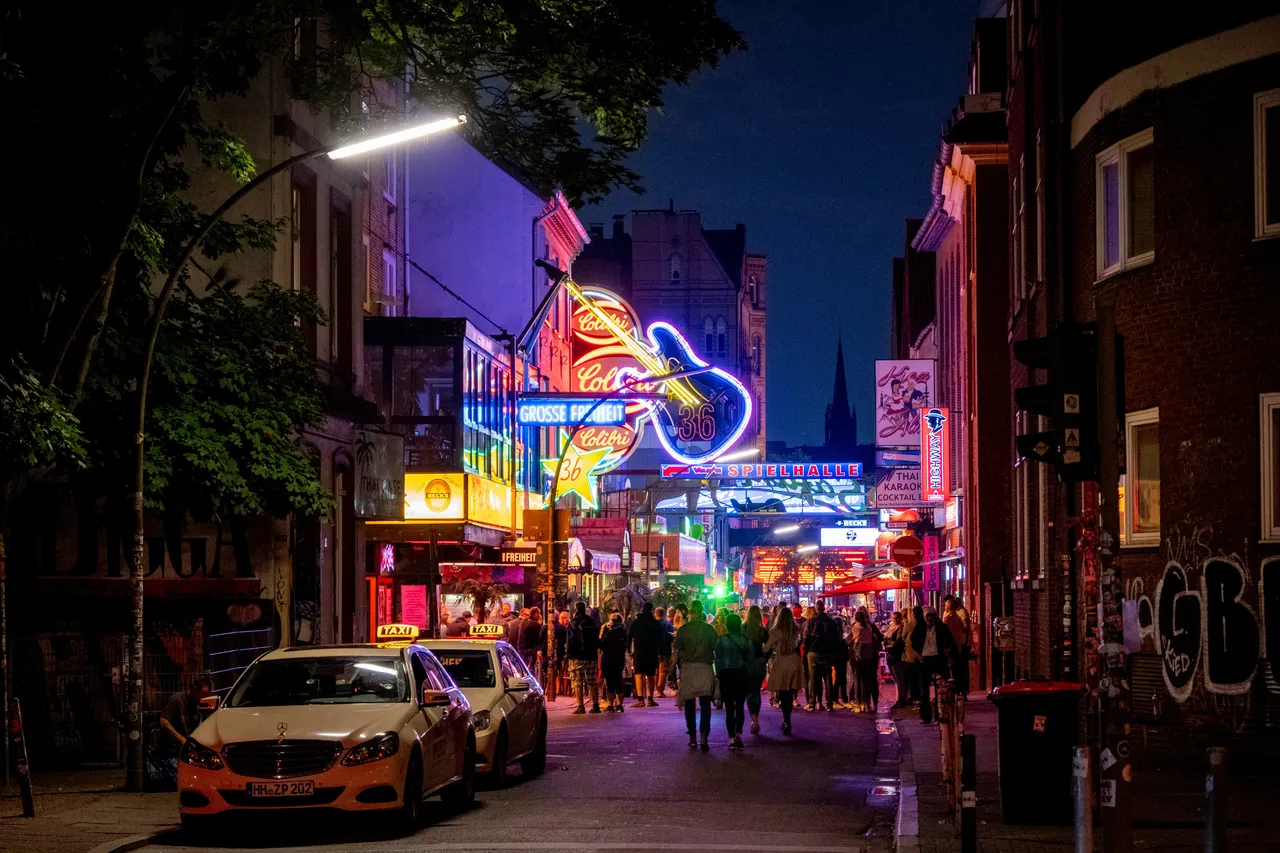 Neon signs light up Hamburg's Reeperbahn nightlife street with taxis and crowds