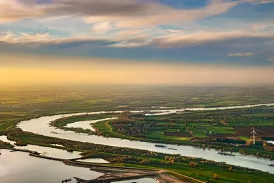 Winding river through a green landscape at sunset, seen from a helicopter