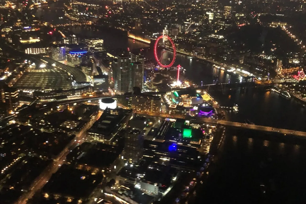 City lights and a river glowing at night, seen from a helicopter
