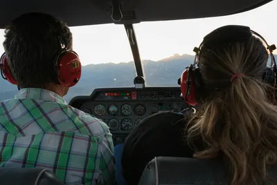 Couple wearing headsets looking out through the cockpit window during a helicopter flight
